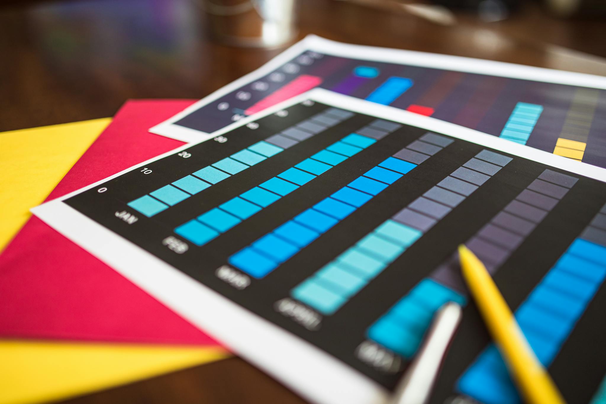 About Close-up of colorful financial charts and a pencil on a wooden desk.